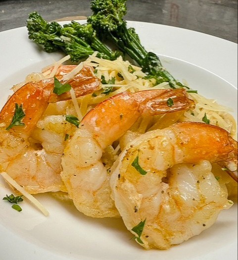Shrimp fried rice served with steamed dumplings and sesame-glazed bok choy on a white plate.